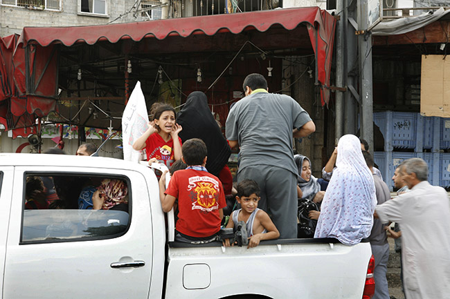 Shocked children and adults pile on to pick up trucks as shelling is ongoing a few hundres meters away.